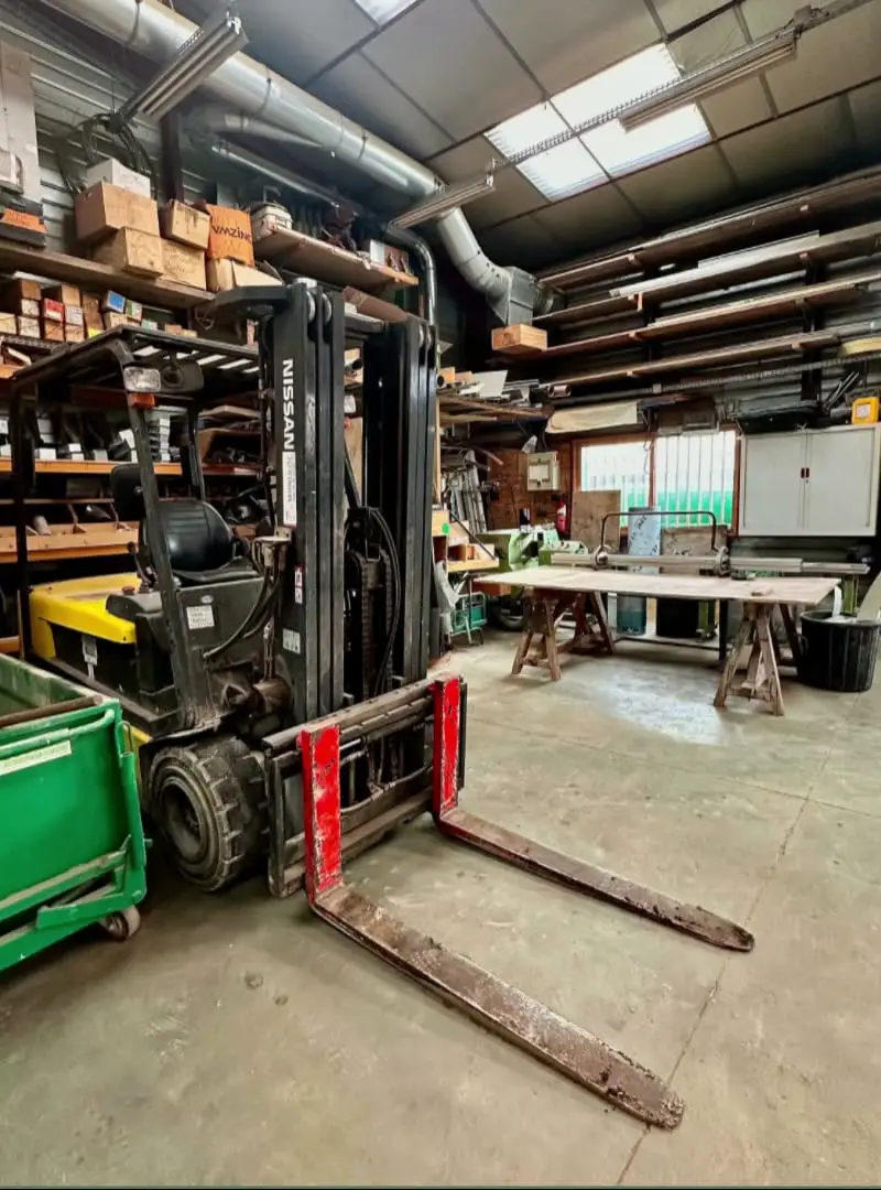 L’atelier de BATI-CHARPENTE à Faremoutiers : établis, machines et rayonnages de bois.